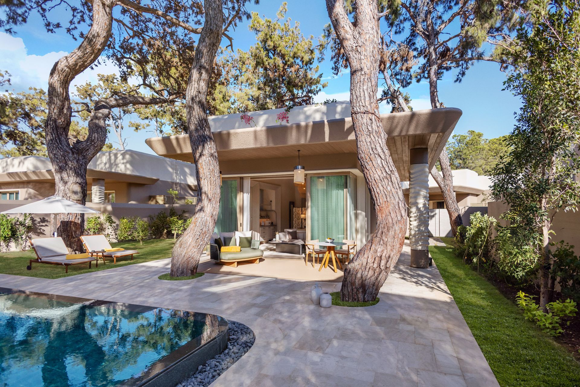 A house with a swimming pool in front of it surrounded by trees.
